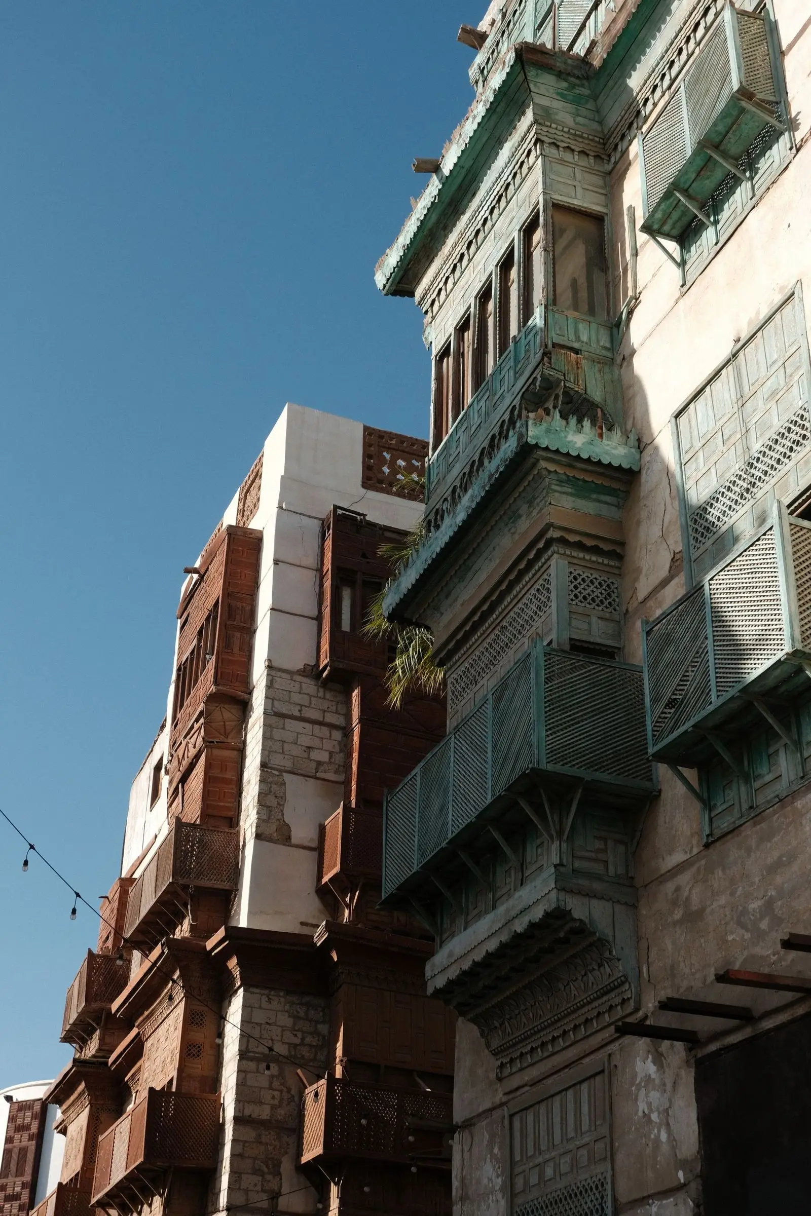 Tall historic houses with wooden window screens on a Jeddah street.