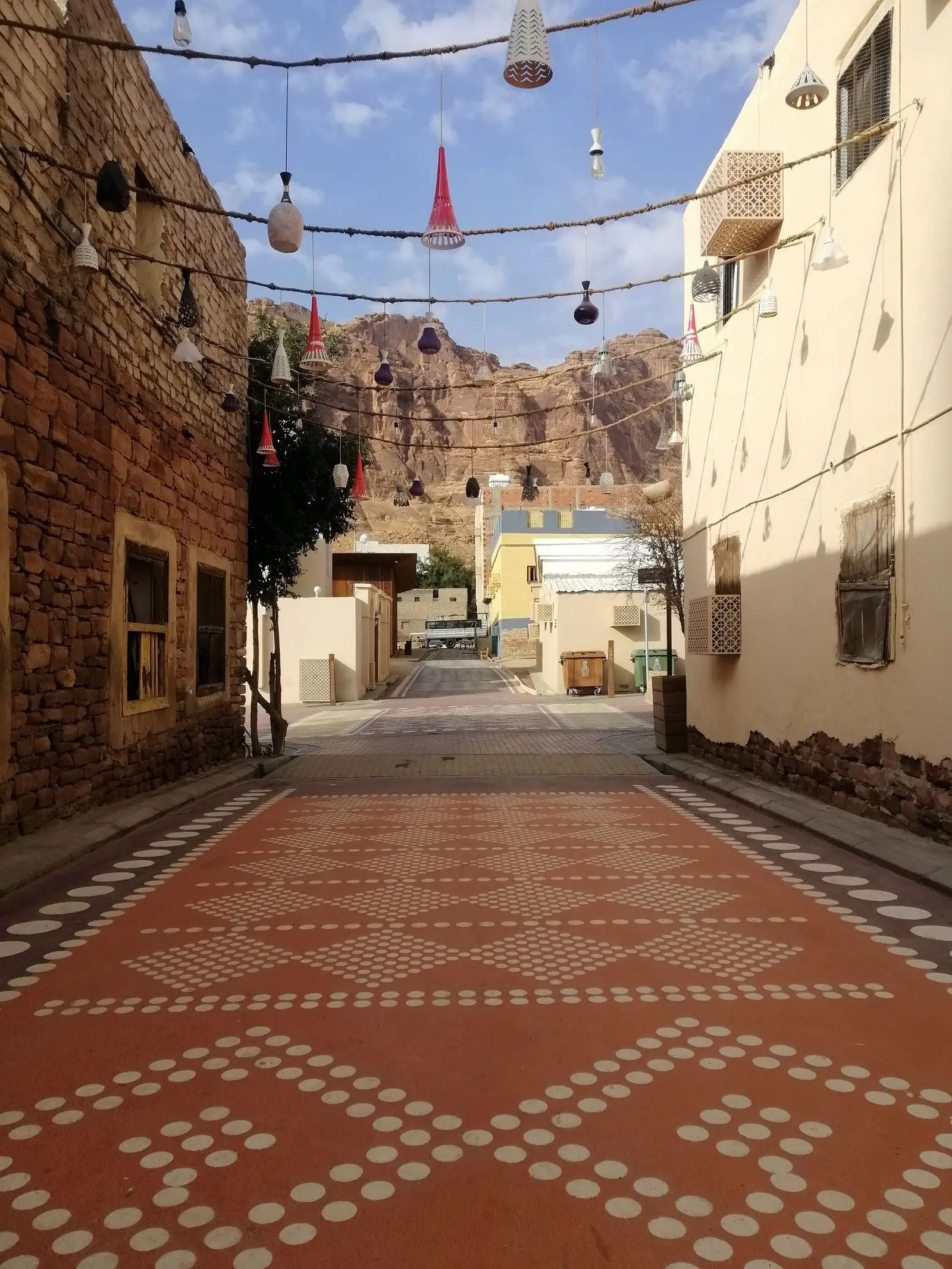 A paved street in AlUla lined with low decorated buildings.