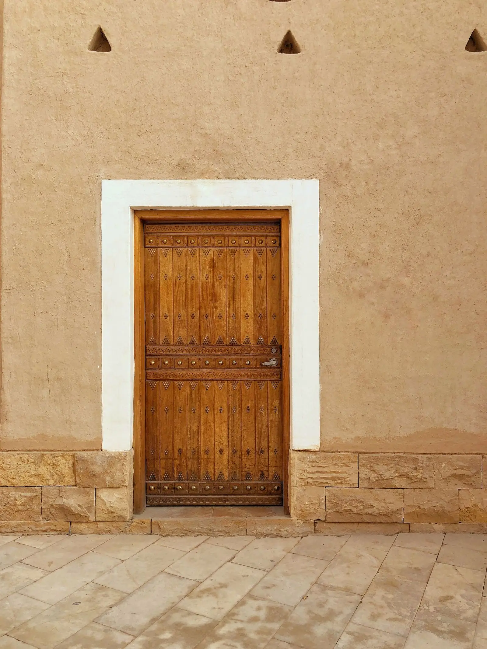 A weathered wooden door set in a thick adobe wall in Diriyah.